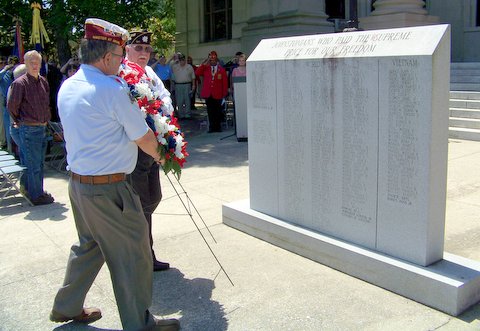 A wreath is placed in front of a monument where the names are inscribed of all Veterans from Johnston County who lost their lives while serving their country.