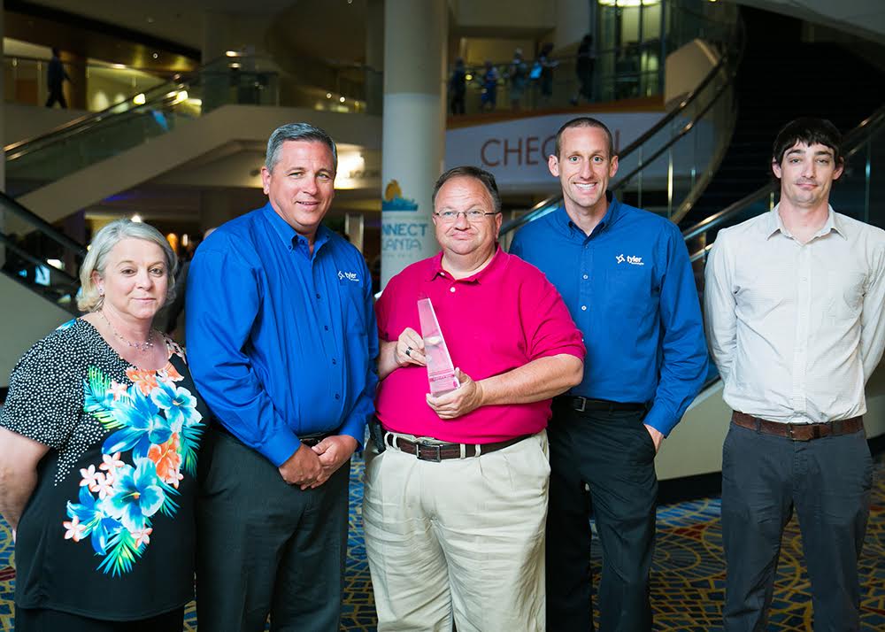 Tyler’s Local Government Division Vice President of Development Jim Adams (L) and Land and Vital Records Product Manager Chris Kelley (R) present a Tyler Excellence Award to North Carolina’s Johnston County Register of Deeds Office’s Patty Woodall, assistant register of deeds, Craig Olive, register of deeds, and Jeff K. Wilson, computer systems analyst.