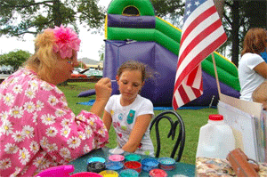 Benson’s Singing Grove was filled with kids on Saturday, anticipating the night’s fireworks display and enjoying the inflatables and ice cream in the meantime. The ever-popular Sybil the Clown was also on hand, twisting up balloon animals and painting faces. In the photo, 11-year-old Laila Whitman get a patriotic design.