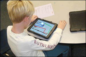 Tanner Broughton, a first grader at South Smithfield Elementary School, programs and Ozobot to tell it how to move using an iPad application.
