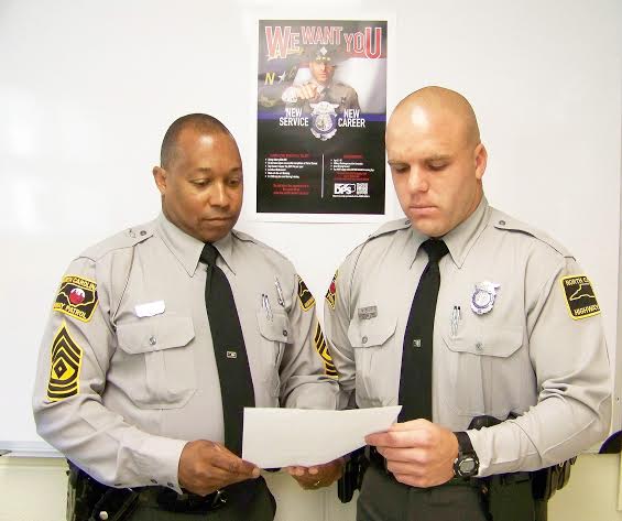 Johnston County Highway Patrol First Sgt. V.E. Burton (left) reads a thank you letter from a motorist assisted by Trooper Joshua Kiser (right) earlier this month on US 70 near Smithfield. JoCoReport.com Photo