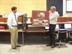 Clayton Mayor Jody McLeod (right) presents two collages to outgoing town manager Steve Biggs (left). JoCoReport.com Photo