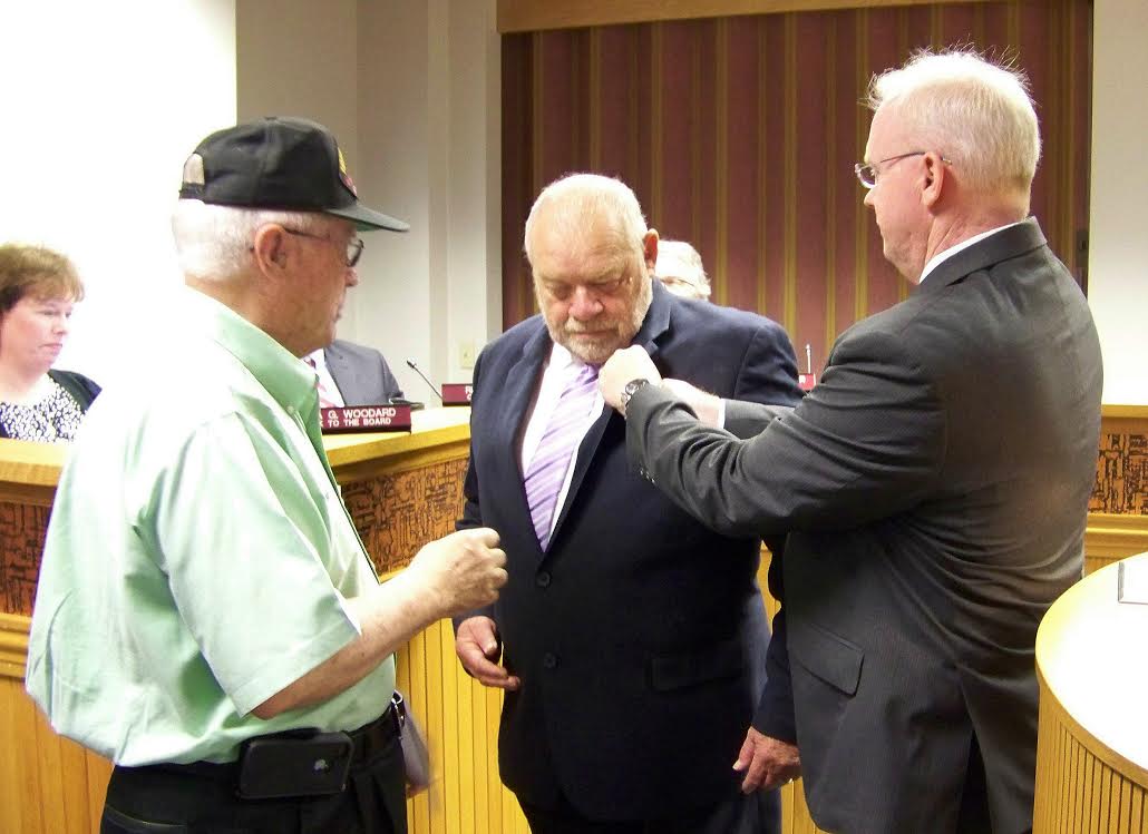 Johnston County Commissioner Chairman Tony Braswell (center) receives his Vietnam Veteran’s Lapel Pin during a surprise presentation from Colonel Rudy Baker (left) and Veterans Administration Director Robert Boyette (right). JoCoReport.com Photo